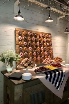 a table topped with lots of donuts next to a wall covered in doughnuts