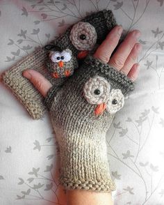 an owl mitt with two small owls on it's palm, laying on top of a bed