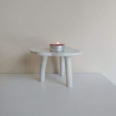 a small white table with a candle on it