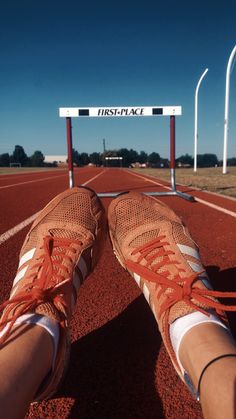 someone's feet resting on the edge of a running track with an empty sign in the background