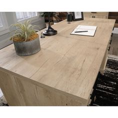 a wooden desk with a plant on top of it and a notepad next to it