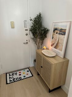 a room with a white door and a wooden cabinet next to a potted plant