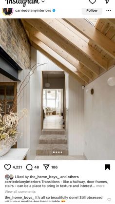 an instagramted photo of a hallway with white walls and wood beams on the ceiling