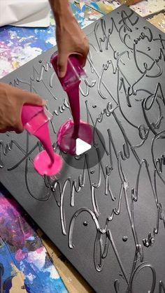 a person is using a pink shoe to decorate a large piece of art on a table