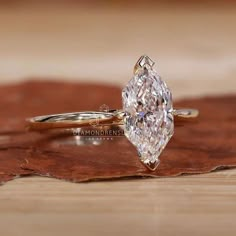 a close up of a diamond ring on a wooden surface