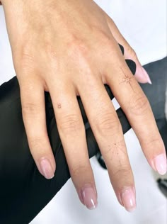 a woman's hand with a cross tattoo on her left wrist and pink nail polish