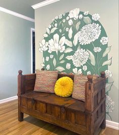 a wooden bench sitting in front of a wall with flowers painted on the walls behind it