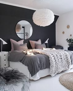 a bedroom with black and white walls, grey bedding, gray pillows and a round mirror on the wall