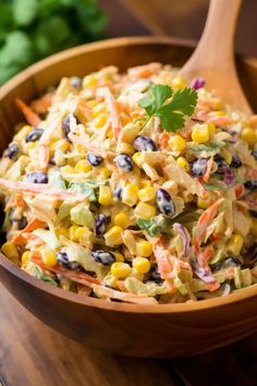 a wooden bowl filled with corn salad and garnished with cilantro