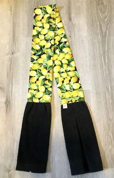 a pair of black pants with yellow lemons on them sitting on top of a wooden floor