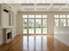 an empty living room with wood floors and large doors leading to the back yard area