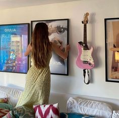 a woman standing in front of three guitars hanging on the wall