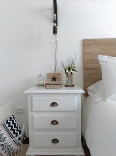 a white night stand with two drawers on each side and a black lamp above it