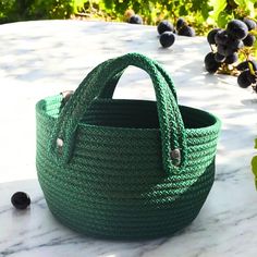 a large green basket sitting on top of a table next to some black berries and leaves