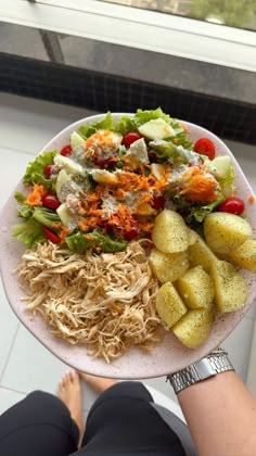 a person holding a plate with different types of food on it in front of a window