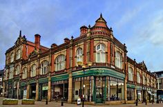 an old brick building on the corner of a street in front of other buildings and shops