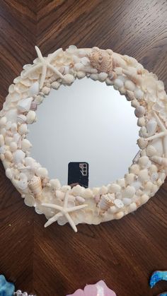 a mirror that is sitting on top of a wooden table next to shells and seashells