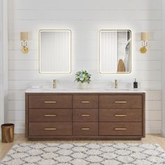 a bathroom with two sinks and mirrors on the wall next to a rug in front of it