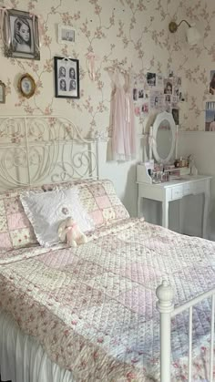 a white bed sitting in a bedroom next to a wall with pictures on the walls