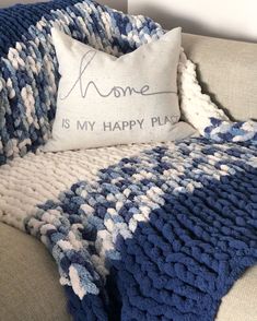 a blue and white blanket sitting on top of a couch next to a pillow that says home is my happy place