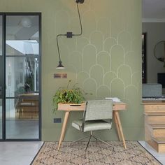 a desk with a plant on it in front of a green wall and stairs that lead up to the second floor