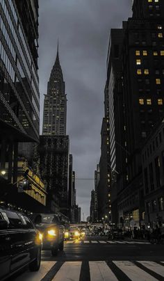 cars are driving down the street in front of tall buildings at night with lights on