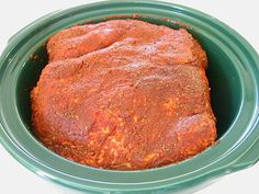 a close up of a meatloaf in a green bowl on a white surface