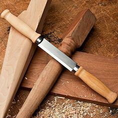 a knife is sitting on top of a cutting board next to some wood shavings