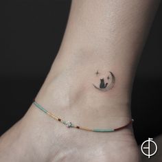 a small tattoo on the ankle of a woman with a cat sitting on top of it