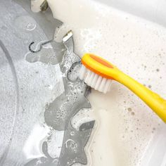 a yellow toothbrush sitting in a bathtub filled with water