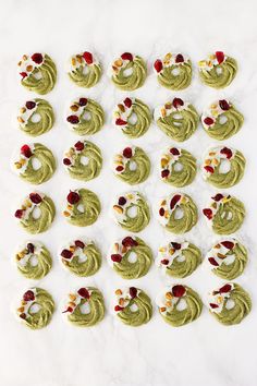 several cookies with green frosting and red cherries on them are arranged in the shape of spirals