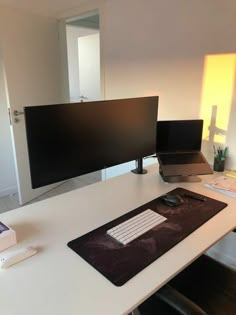 a computer desk with a laptop, monitor and keyboard on it in an office setting