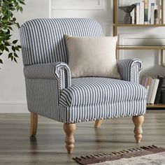 a blue and white striped chair sitting on top of a hard wood floor next to a potted plant