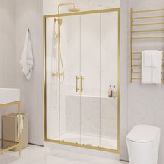 a white and gold bathroom with a glass shower door, toilet and towel rack on the wall