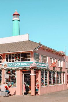 a pink building with a light house on top and people standing outside the front door