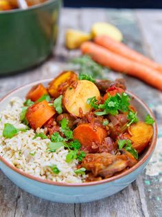 a bowl filled with rice and vegetables on top of a table next to carrots