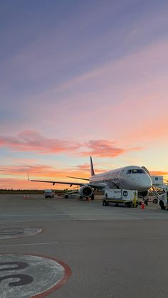 an airplane is parked on the tarmac at sunset