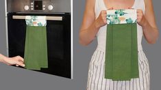 a woman holding up a green towel in front of an oven