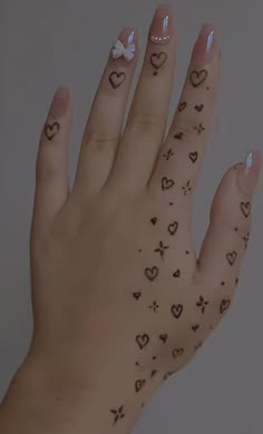 a woman's hand with hearts and bows on her fingers, which are decorated with tattoos