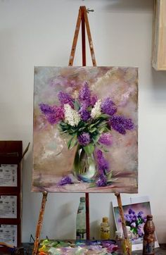 an easel is holding a painting with purple and white flowers in it