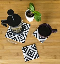 two coasters with black and white designs on them next to a potted plant