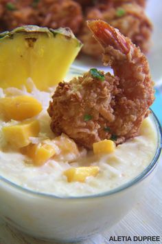 a bowl filled with oatmeal topped with fried shrimp and pineapple slices