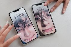 two cell phones with the faces of people on them are being held up by someone's hands