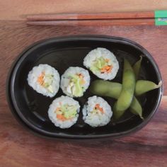 sushi is served in a black bowl with chopsticks