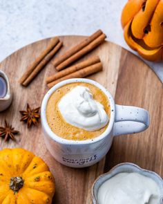 pumpkin spice latte with whipped cream in a mug and cinnamon sticks on the side