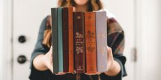 a woman holding four books in her hands