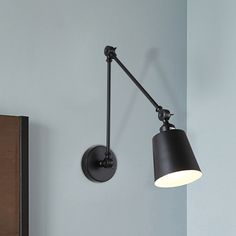 a black wall light hanging from the side of a bed next to a night stand