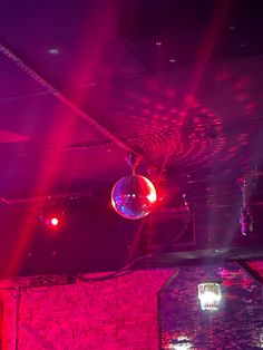 disco ball hanging from the ceiling in a club with red and purple lights on it