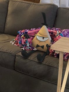 an odd looking stuffed animal laying on top of a couch next to a wooden table