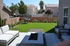 an outdoor living area with white furniture and artificial grass in the back yard on a sunny day